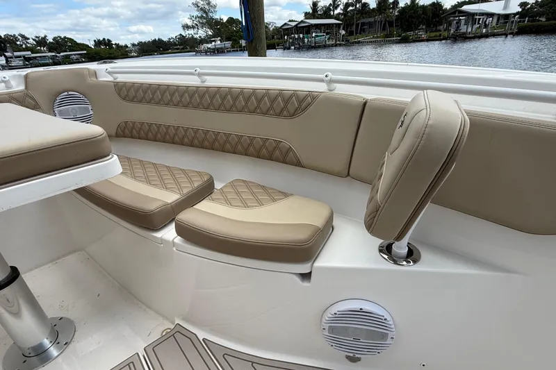 Slide: The Image of 2023 Sea Pro 320 DLX Offshore boat interior with beige cushioned seating and speaker. - 75