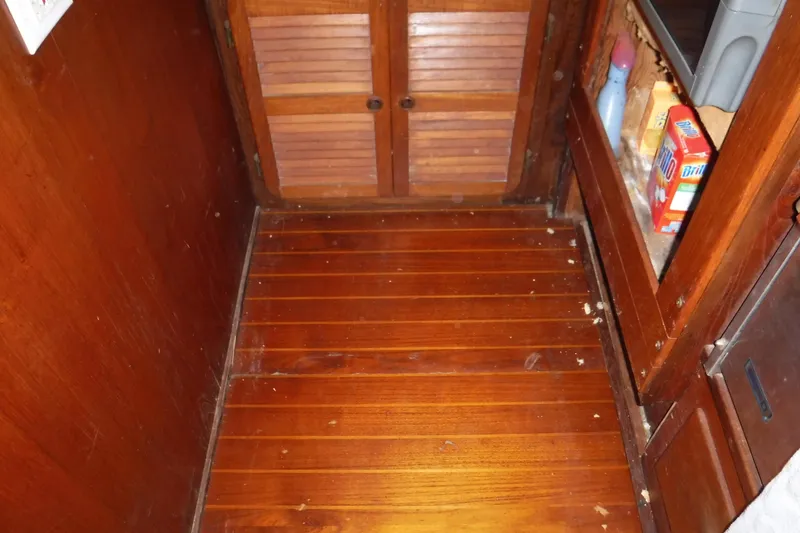 Slide: The Image of Wooden interior of 1988 Dudley Dix Echo 38 sailboat, featuring storage and cleaning supplies. - 20