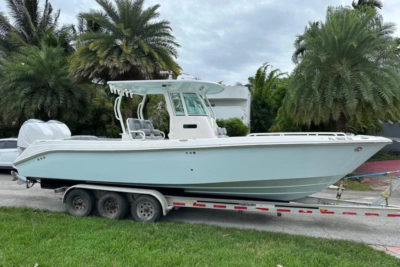 The Image of 2006 Everglades 290 Center Console boat on trailer, surrounded by palm trees. - 1