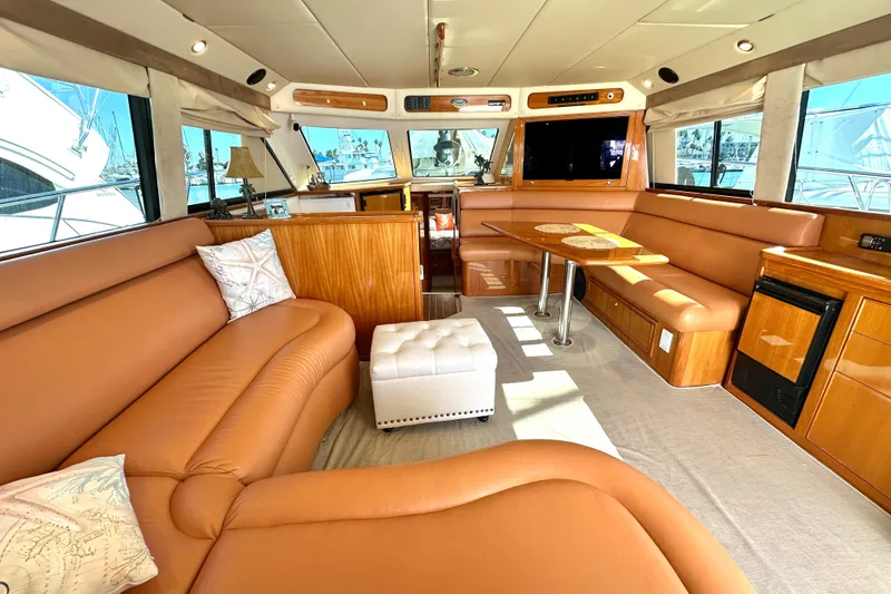 Slide: The Image of 2005 Riviera 47 Open Flybridge yacht on water near rocky shoreline. - 2