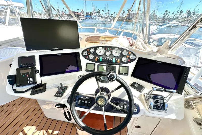 Slide: The Image of 2005 Riviera 47 Open Flybridge yacht with clear enclosure and blue seats under a bright sky. - 24