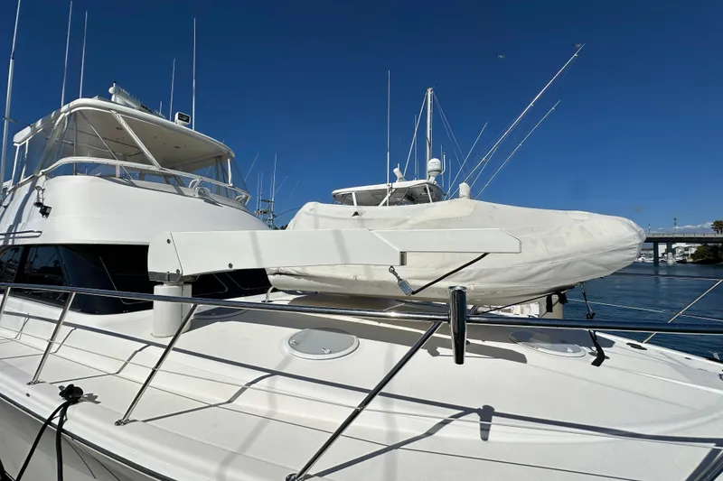 Slide: The Image of 2005 Riviera 47 Open Flybridge interior with wooden table, cushioned seating, and marina view. - 30