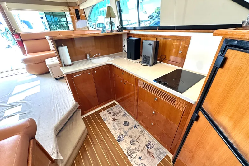 Slide: The Image of Interior of 2005 Riviera 47 Open Flybridge yacht with wood cabinetry and marina view. - 9