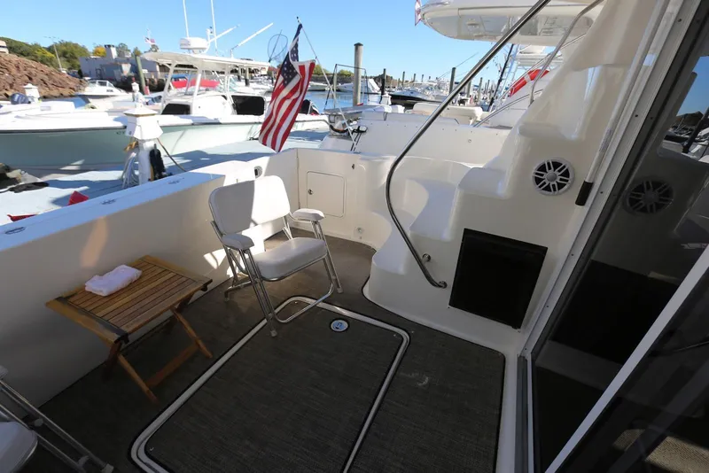 Slide: The Image of 2004 Sea Ray 420 Sedan Bridge yacht deck with chairs and American flag. - 10