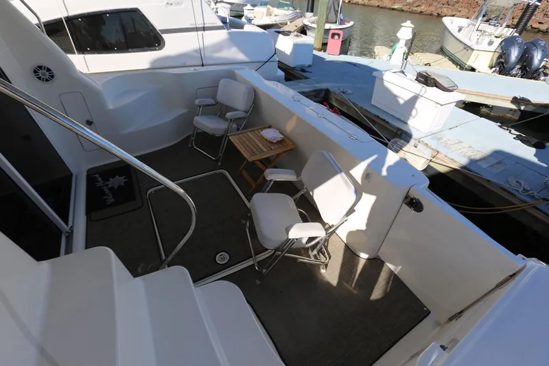 Slide: The Image of 2004 Sea Ray 420 Sedan Bridge yacht deck with chairs and table, docked at marina. - 13