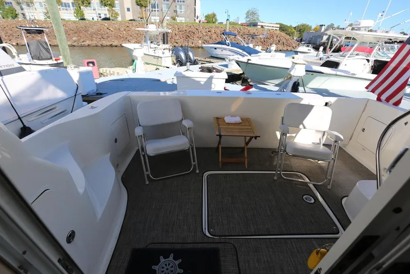 Slide: The Image of 2004 Sea Ray 420 Sedan Bridge yacht deck with chairs and table, docked at marina. - 21
