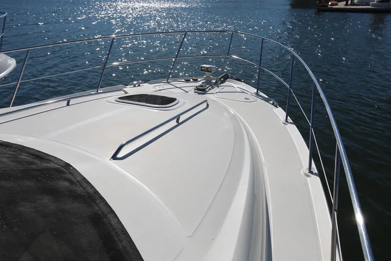 Slide: The Image of 2004 Sea Ray 420 Sedan Bridge yacht deck with railing, glistening on calm water. - 22