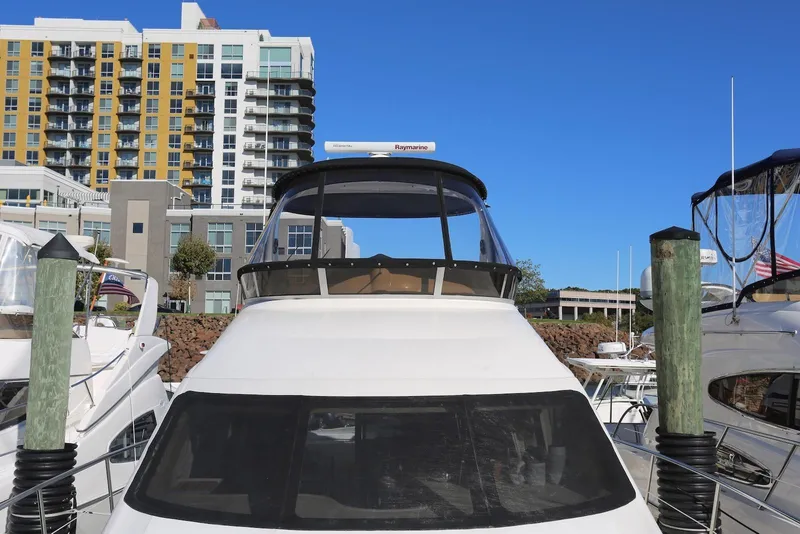 Slide: The Image of 2004 Sea Ray 420 Sedan Bridge yacht docked at marina with modern buildings in background. - 24