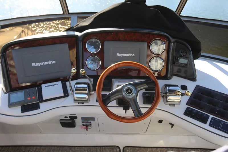 Slide: The Image of 2004 Sea Ray 420 Sedan Bridge helm with Raymarine displays and wooden steering wheel. - 38
