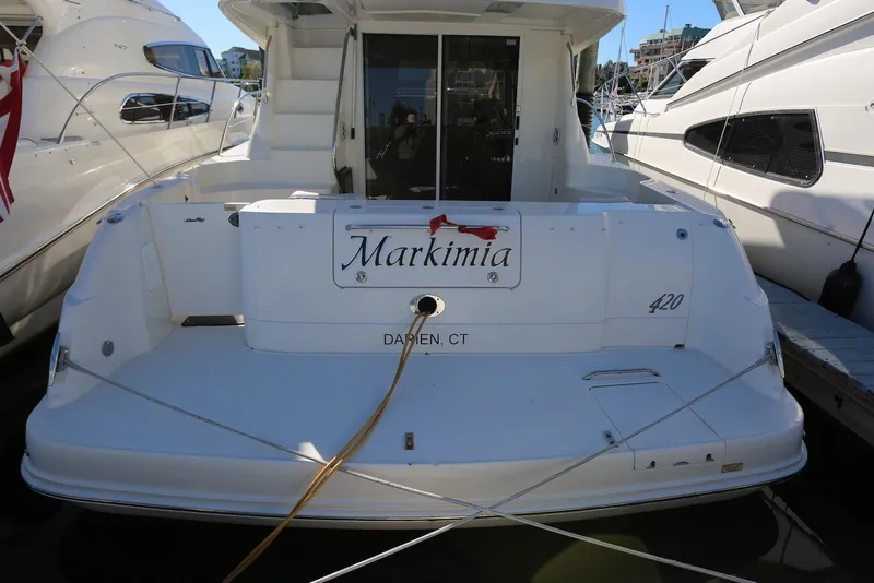 Slide: The Image of 2004 Sea Ray 420 Sedan Bridge docked, rear view with "Markimia" nameplate. - 5