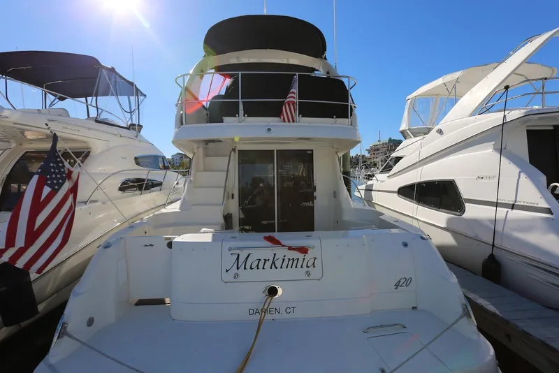 Slide: The Image of 2004 Sea Ray 420 Sedan Bridge yacht docked, rear view with American flag. - 6