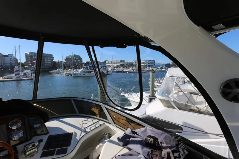 Slide: The Image of 2004 Sea Ray 420 Sedan Bridge interior view at marina, overlooking docked boats and waterfront buildings. - 62