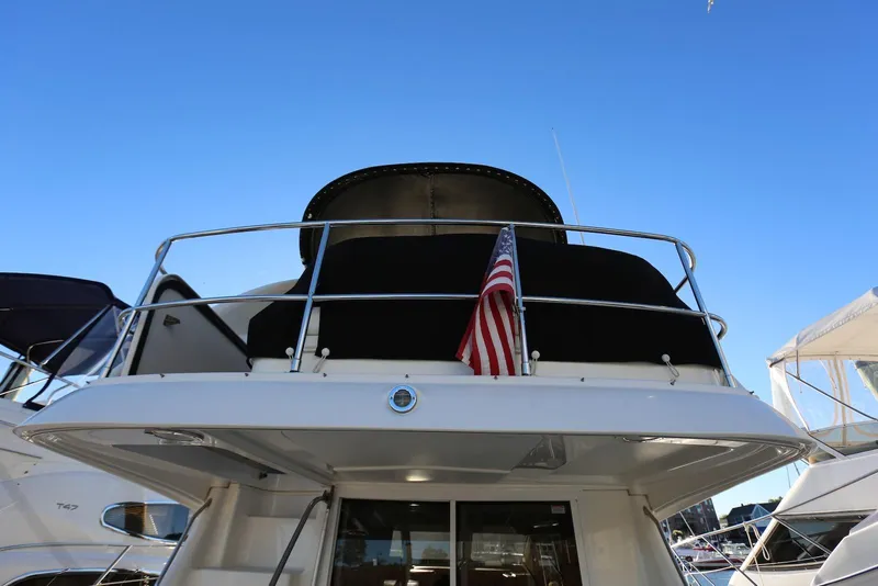 Slide: The Image of 2004 Sea Ray 420 Sedan Bridge yacht with American flag, docked under clear blue sky. - 7