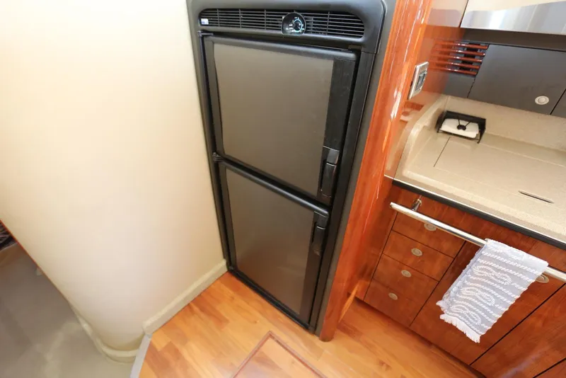 Slide: The Image of 2004 Sea Ray 420 Sedan Bridge kitchen with fridge and wooden cabinetry. - 77