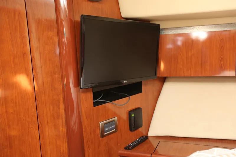 Slide: The Image of 2004 Sea Ray 420 Sedan Bridge interior with mounted TV and wooden paneling. - 84
