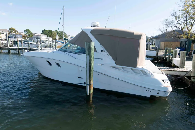 The Image of 2009 Sea Ray 310 Sundancer yacht docked at marina, covered, calm water. - 0