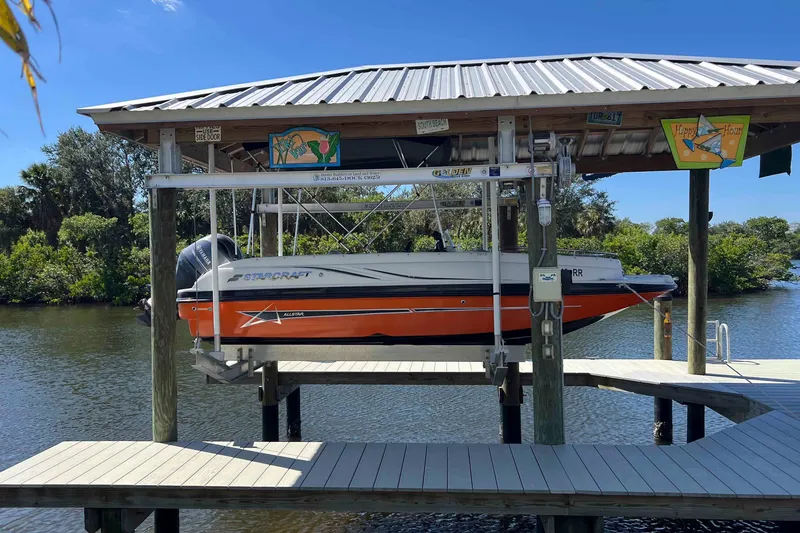 The Image of 2018 Starcraft SVX 190 OB boat on lift, docked by a scenic waterway. - 0