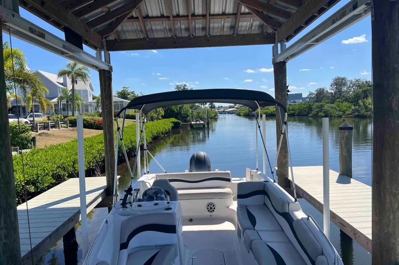 Slide: The Image of 2018 Starcraft SVX 190 OB boat docked under a covered pier on a sunny day. - 13