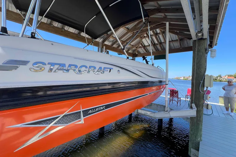 Slide: The Image of 2018 Starcraft SVX 190 OB boat docked under a wooden shelter by the water. - 3