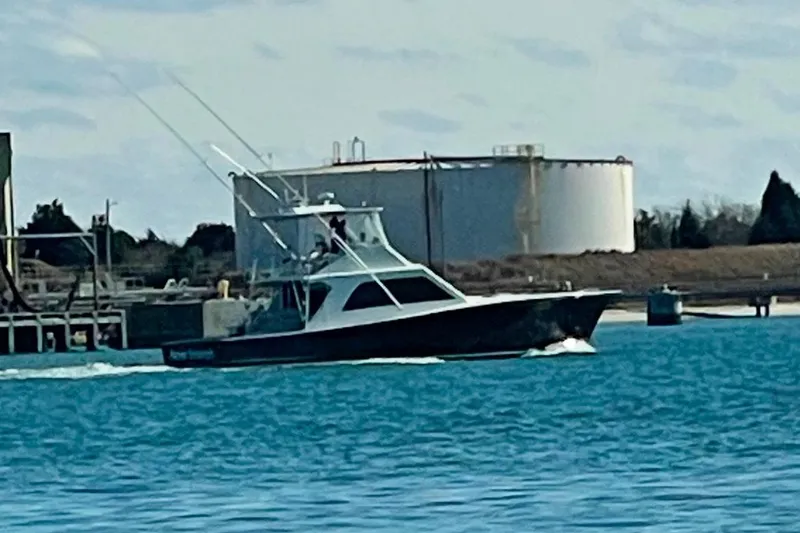 Slide: The Image of 1984 Tiffany 50 Convertible boat cruising near industrial waterfront. - 2