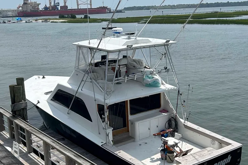 Slide: The Image of 1984 Tiffany 50 Convertible yacht docked by the waterfront with industrial ships in the background. - 4