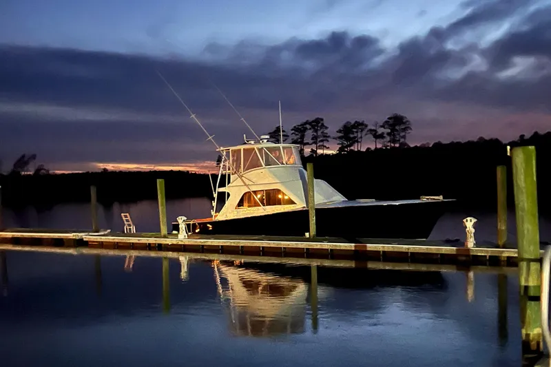 Slide: The Image of 1984 Tiffany 50 Convertible yacht docked at sunset, reflecting on calm water. - 6