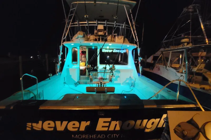 Slide: The Image of 1984 Tiffany 50 Convertible yacht "Never Enough" docked at night, illuminated with blue lights. - 7