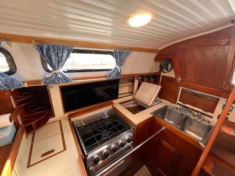 Slide: The Image of 1981 Ericson 38 yacht interior kitchen with stove, sink, and wooden cabinetry. - 21