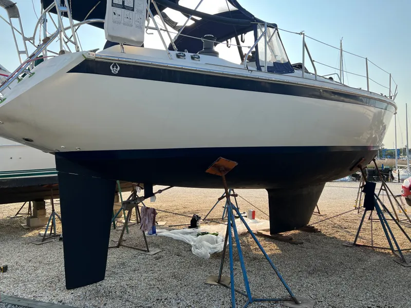 Slide: The Image of 1981 Ericson 38 sailboat on stands, hull visible, in a boatyard setting. - 4