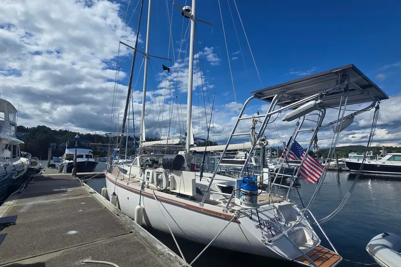 The Image of Sailboat Amel Santorin 1993 docked at marina, clear sky, American flag displayed. - 0