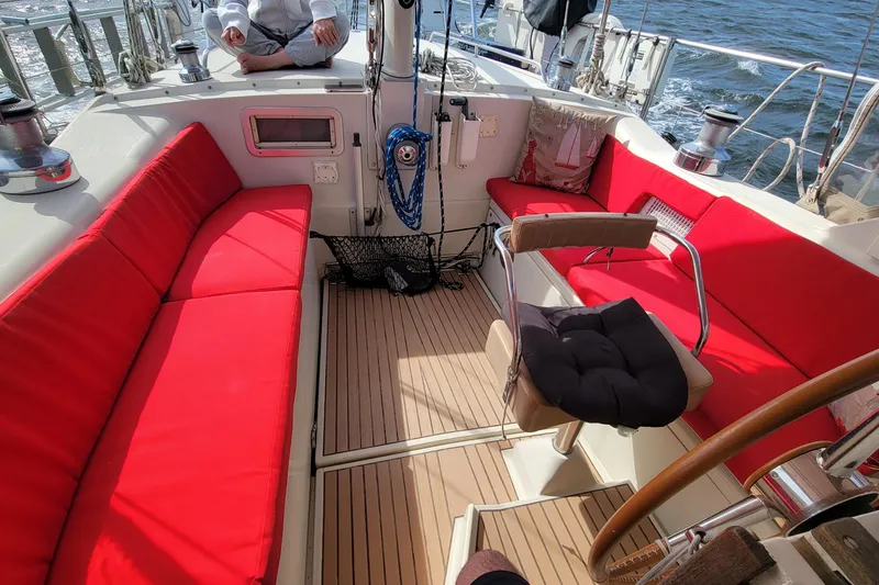 Slide: The Image of Cockpit of 1993 Amel Santorin sailboat with red cushions and wooden flooring. - 11