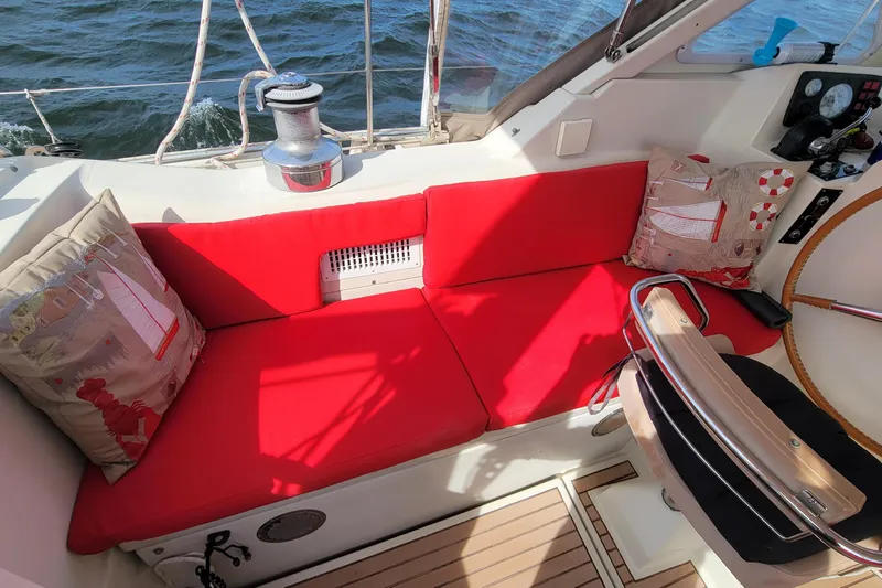 Slide: The Image of Cozy cockpit of 1993 Amel Santorin sailboat with red cushions and nautical-themed pillows. - 12