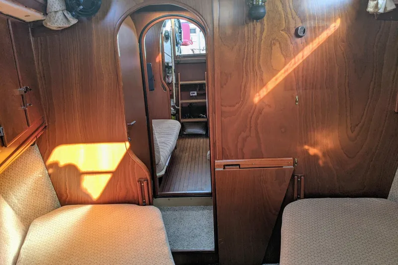 Slide: The Image of Interior of a 1993 Amel Santorin sailboat with wooden paneling and cozy seating. - 23