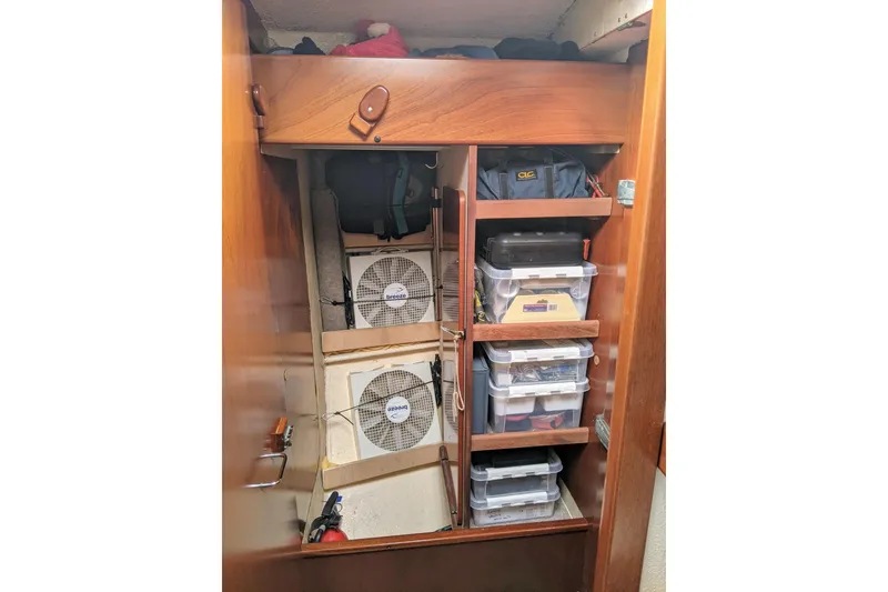 Slide: The Image of Storage area in a 1993 Amel Santorin yacht with organized shelves and cooling fans. - 25