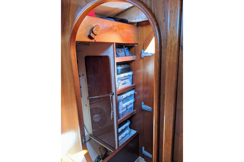 Slide: The Image of Interior storage area of a 1993 Amel Santorin sailboat with wooden shelves and organized containers. - 26