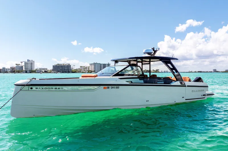 Slide: The Image of 2021 Saxdor 320 GTO boat on turquoise water with city skyline in background. - 3