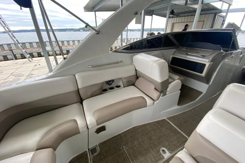 Slide: The Image of 2015 Crownline 335 SS boat interior with beige seating and dashboard. - 17