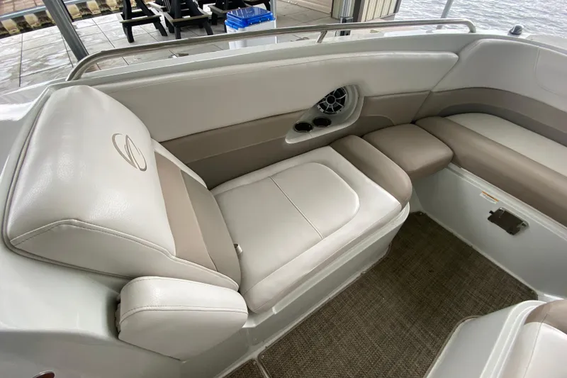 Slide: The Image of 2015 Crownline 335 SS boat interior with beige seating and speaker, dockside view. - 35