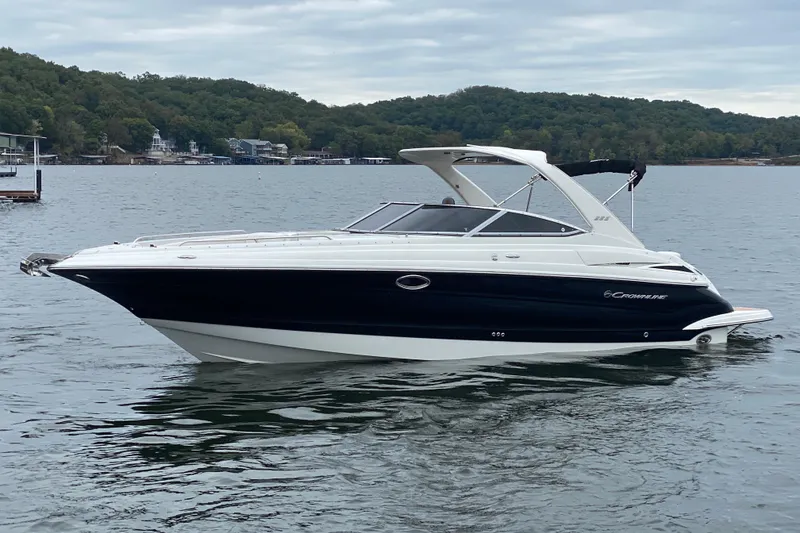 Slide: The Image of 2015 Crownline 335 SS boat on a calm lake with forested shoreline. - 4