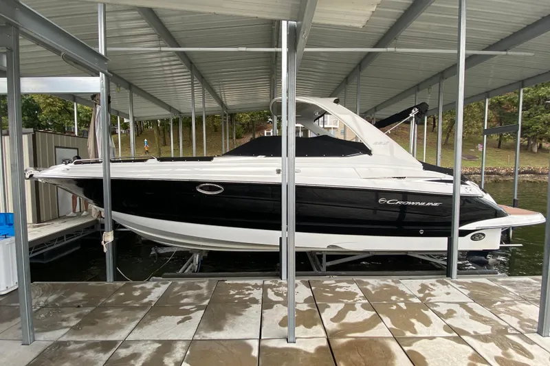 Slide: The Image of 2015 Crownline 335 SS boat docked, featuring sleek black and white design. - 8
