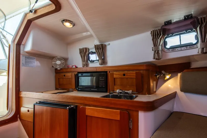 Slide: The Image of 2005 Hunt Yachts Surfhunter 29 interior with kitchenette, featuring wood cabinetry and modern amenities. - 24