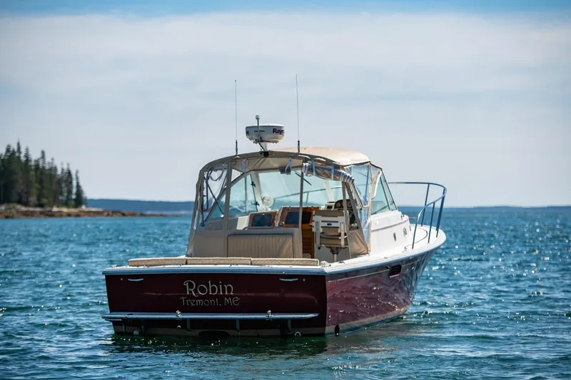 Slide: The Image of 2005 Hunt Yachts Surfhunter 29 on calm water, rear view, with coastal background. - 3