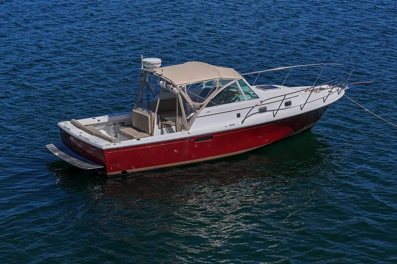 Slide: The Image of 2005 Hunt Yachts Surfhunter 29 boat on blue water, featuring a red hull and beige canopy. - 4
