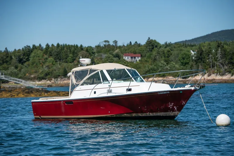 Slide: The Image of 2005 Hunt Yachts Surfhunter 29 in scenic coastal waters, anchored near lush greenery. - 1