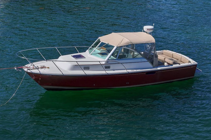 Slide: The Image of 2005 Hunt Yachts Surfhunter 29 boat on calm water, featuring a sleek design and beige canopy. - 5
