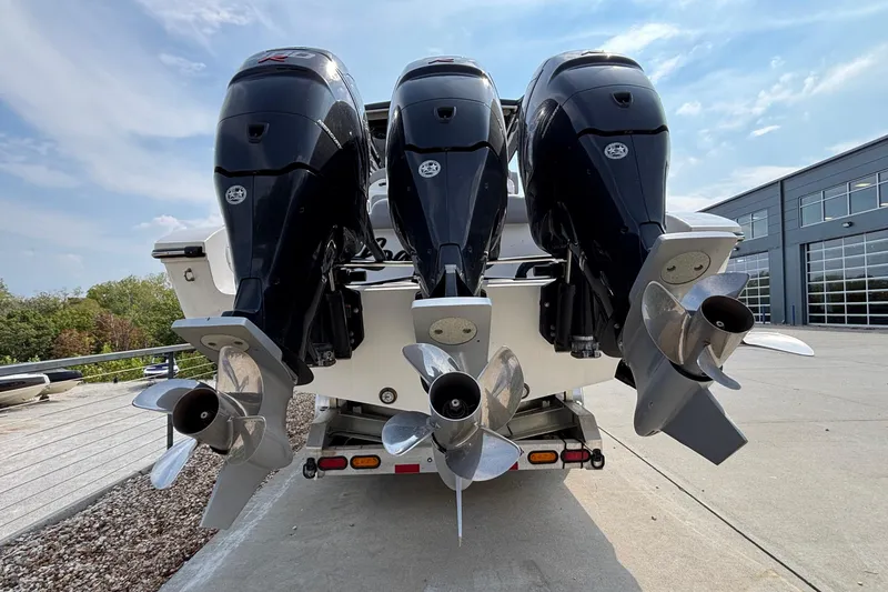 Slide: The Image of Triple outboard motors on a 2022 Fountain 38 SC boat, parked outdoors. - 6