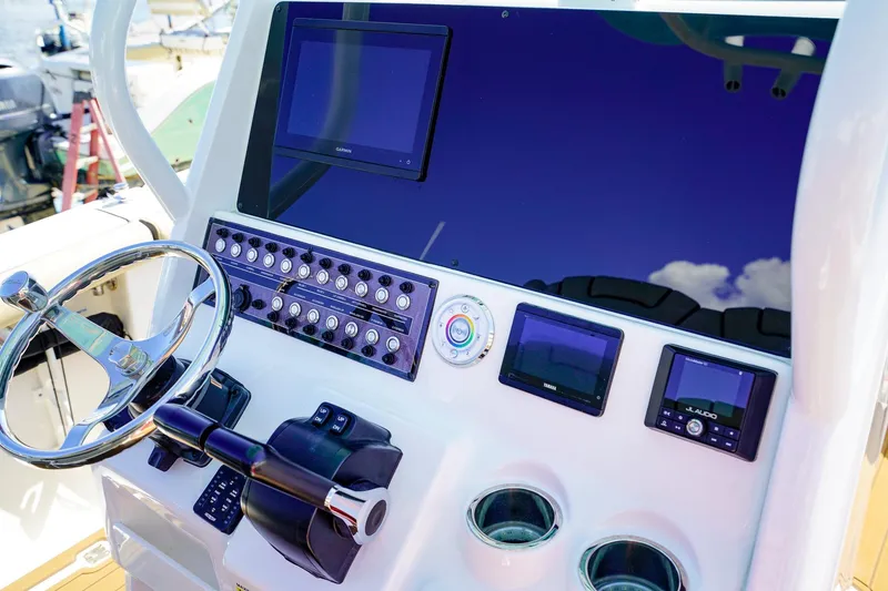 Slide: The Image of 2021 Tidewater 256 LXF boat dashboard with steering wheel and electronic controls. - 13