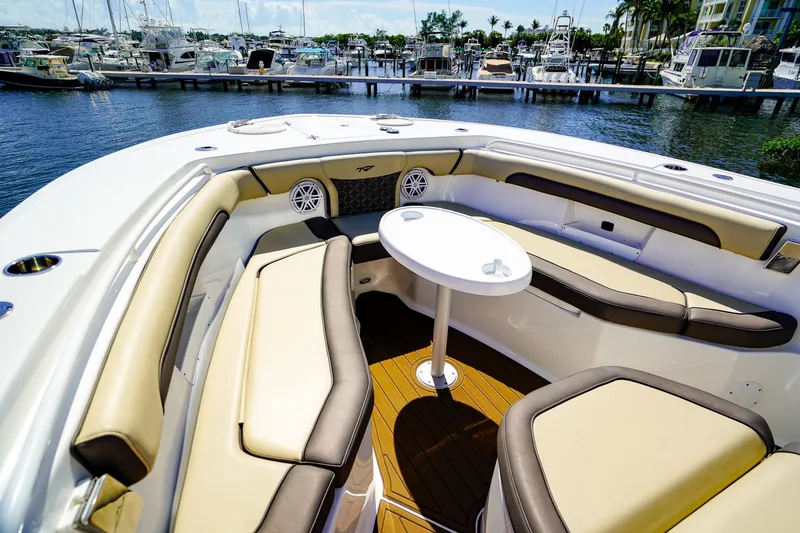 Slide: The Image of 2021 Tidewater 256 LXF boat interior with cushioned seating and table, docked at marina. - 20