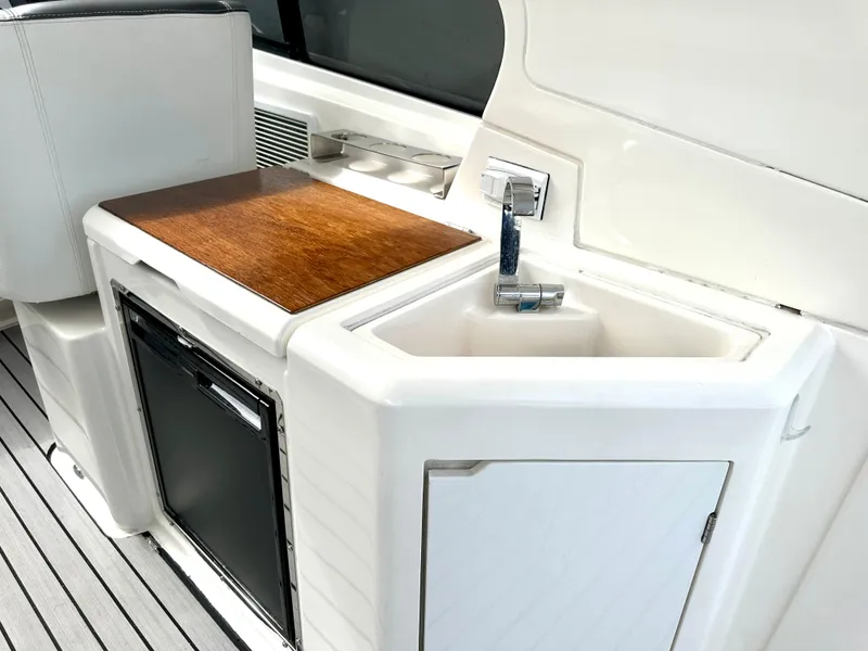 Slide: The Image of Bavaria Sport 360 HT 2016 yacht kitchenette with sink, faucet, mini-fridge, and wooden countertop. - 36