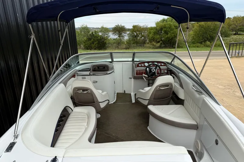Slide: The Image of 2005 Cobalt 240 boat interior with white seating, blue canopy, and wood-accented dashboard. - 11